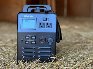 Patriot Power Solar Generator 1800 front view on a barn hay floor, portable solar power station with AC outlets and USB ports for off-grid and emergency backup power