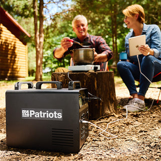 Patriot Power Solar Generator 1800 close-up at a campsite powering a camp hot plate and tablet for a couple, compact off-grid portable solar backup power station