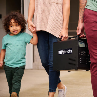 Woman and child walk outdoors as she carries the Patriot Power Solar Generator 1800, a portable solar generator for off-grid family emergency backup power