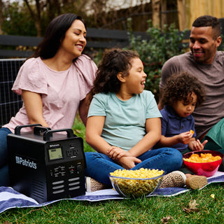 Family enjoys a backyard picnic beside the Patriot Power Solar Generator 1800 portable solar power station for off-grid and emergency backup power