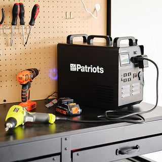 Patriot Power Solar Generator 1800 on a workbench beside a cordless drill and lithium batteries, portable solar generator supplying off-grid power to workshop tools