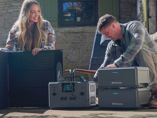 Expansion Battery Pack for Patriot Power Generator 2200X, wide porch scene of a couple with two packs, the 2200X and a 200W solar panel for off-grid emergency backup