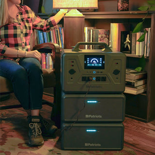 Expansion Battery Pack for Patriot Power Generator 2200X, tight crop of two packs stacked under the 2200X keeping a lamp lit as a woman reaches for it during a blackout