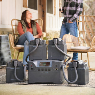 Patriot Power Generator 2500X with four Expansion Battery Packs connected, powering a porch gathering with an outdoor AC unit