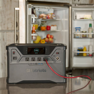 Patriot Power Solar Generator 2500X on a counter powering an open refrigerator via red cable at 100% charge, portable solar generator for emergency backup power
