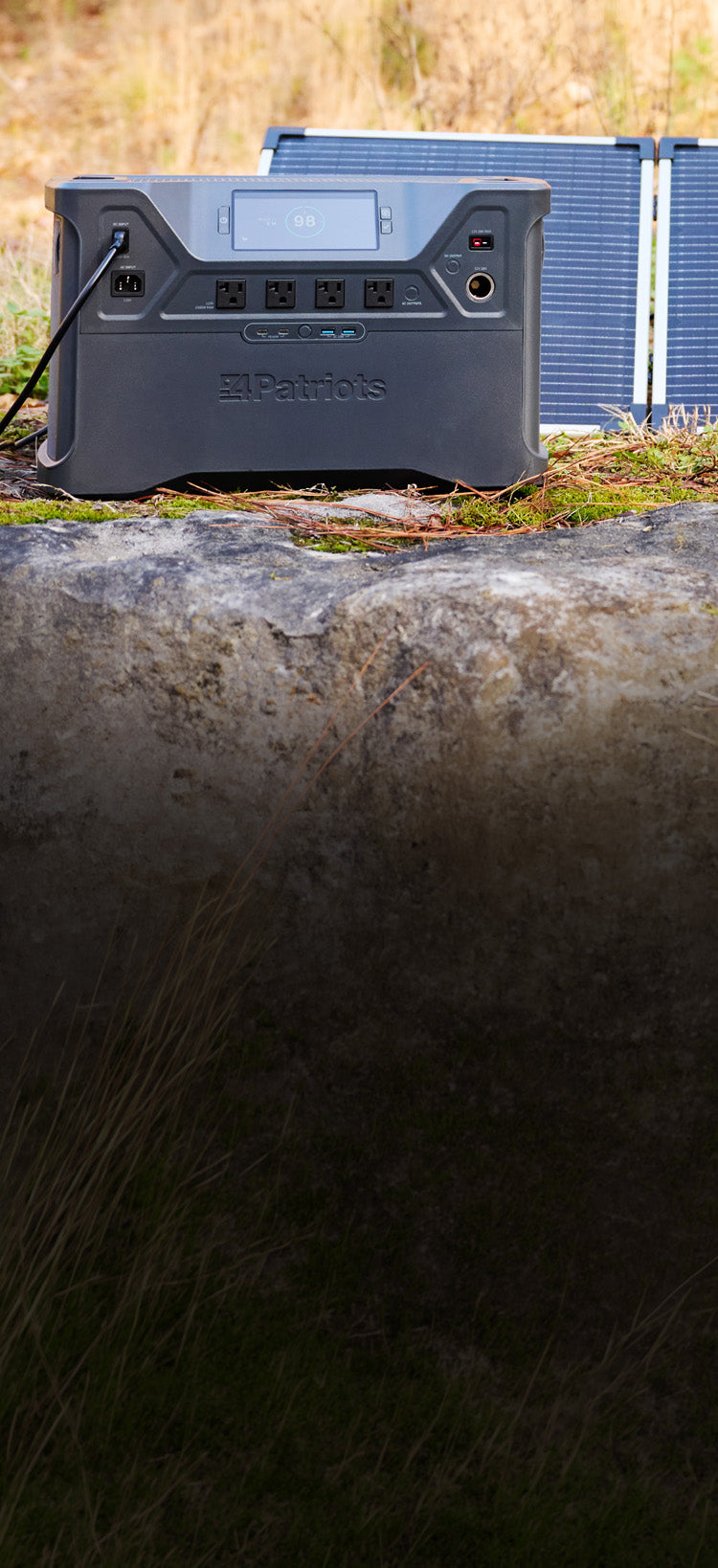 Translation missing: en.Patriot Power Solar Generator 2500X on a mossy boulder in a field with a folding solar panel behind it, off-grid portable solar generator charging for emergency backup power