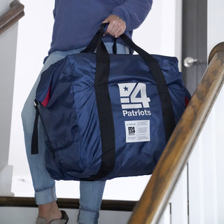 Woman carrying the navy EMP protection bag included with the Expansion Pack Platinum Elite Upgrade down a staircase
