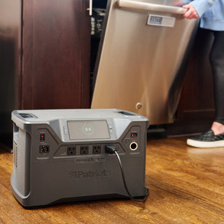 Patriot Power Solar Generator 2000X on the kitchen floor running a stainless steel dishwasher, showing the portable solar generator's off-grid emergency backup power for appliances