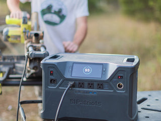Man running a power tool outdoors from the Patriot Power Solar Generator 2000X on a worksite table, portable solar generator delivering off-grid jobsite and emergency power