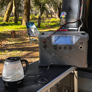 Patriot Power Solar Generator 2000X powering an electric coffee pot at a wooded campsite tailgate, portable solar power station for off-grid camping and emergency backup