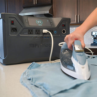 Patriot Power Solar Generator 2000X on a kitchen counter powering a clothing iron, demonstrating portable solar off-grid emergency backup power for everyday household appliances