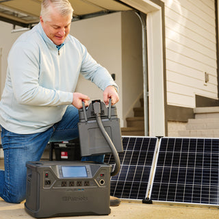 Man placing an Expansion Battery Pack onto a Patriot Power Generator 2000X connected to a solar panel in the garage