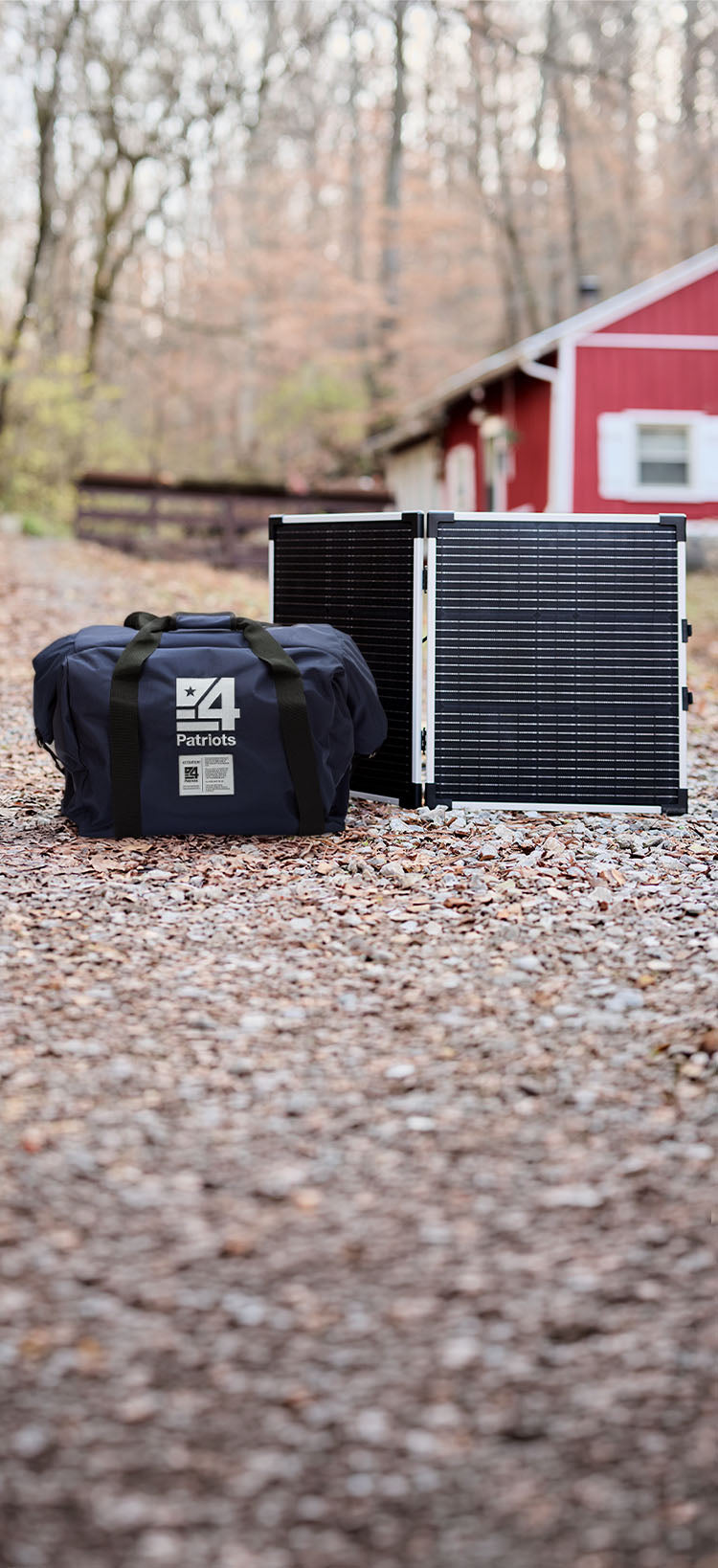 Translation missing: en.Vertical view of Patriot Power Generator Platinum Upgrade gear, a folding solar panel and EMP bag, on a wooded gravel drive by a barn