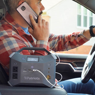 Patriot Power Generator 1800 + Sidekick Kit: Sidekick portable power station on a truck seat at 100% charge powering a driver's phone, mobile emergency backup power