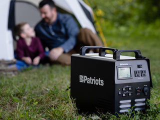 Patriot Power Generator 1800 + Sidekick Kit: the 1800 generator in the grass as a father and son relax in a tent, off-grid camping and emergency backup power