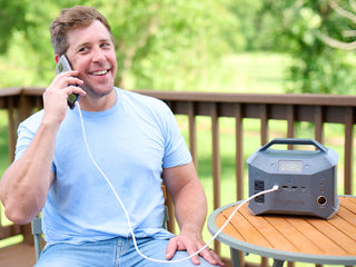 Patriot Power Generator 1800 + Sidekick Kit: man on a deck talks on a phone charging from the Sidekick portable power station, off-grid emergency backup power
