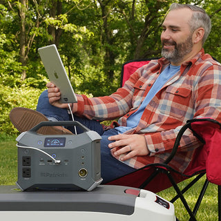 Patriot Power Generator 1800 + Sidekick Kit: camper relaxes outdoors charging an iPad from the Sidekick portable power station for off-grid solar backup power