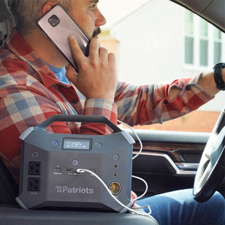 Patriot Power Generator 2000X + Sidekick Kit: close-up of the Sidekick portable power station in a truck cab charging a phone while a man drives, portable backup power