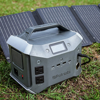 Patriot Power Sidekick portable power station on grass connected to its unfolded 40W solar panel, a portable solar generator for off-grid charging