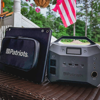 Patriot Power Sidekick and folded solar panel carry case on a porch table beside an American flag, a portable solar generator for home backup