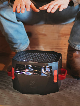 Man warms his hands over the RescueHeat Emergency Space Heater & Stove indoors, a compact fuel-can space heater for staying warm during a power outage