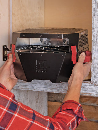 Hands storing the RescueHeat Emergency Space Heater & Stove in a cabinet, a compact space-saving emergency heater and stove ready for off-grid preparedness