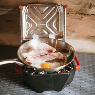 RescueHeat Emergency Space Heater & Stove cooking bacon and an egg in a skillet, a compact off-grid cook stove for hot meals during power outages