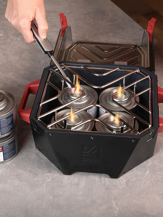 RescueHeat Canned Heat & Chafing Fuel cans lit inside the RES emergency stove unit on a kitchen counter, using a long lighter for indoor power outage cooking