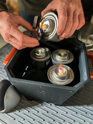 Close-up of lighting RescueHeat Canned Heat & Chafing Fuel cans with a lighter inside the RES heater, emergency chafing fuel for off-grid cooking and heating