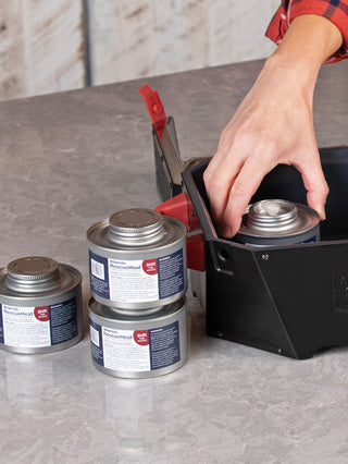 Placing a RescueHeat Canned Heat & Chafing Fuel can into the RES emergency stove on a kitchen counter, canned cooking fuel ready for power outage preparedness