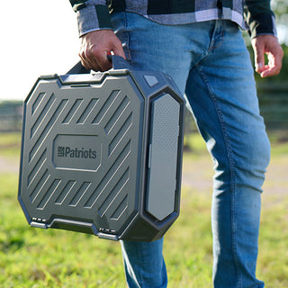 Silver Star Emergency Survival Package: man carrying the hard-shell 4Patriots AlphaCase power station by its handle across a field at sunset, off-grid power