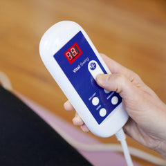 Person holding the Vital Swing Therapeutic Wellness Machine remote in their hand to turn it on
