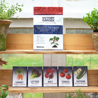 4Patriots Victory Garden Seed Collection bag displayed on a wooden shelf in a greenhouse alongside five individual seed packets for Carrot Scarlet Nantes, Lettuce Red Sails, Beet Detroit Dark Red, Tomato Red Cherry, and Zucchini Black Beauty