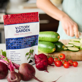 4Patriots Victory Garden Seed Collection bag on a kitchen counter surrounded by fresh beets, cherry tomatoes, and zucchini being sliced in the background