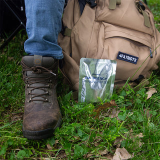 Emergency Drinking Water Pouches - 3-Day Supply pouch resting against a 4Patriots backpack beside a hiking boot outdoors, portable survival water