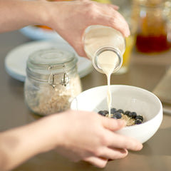 Milk being poured into bowl of oatmeal and blueberries.