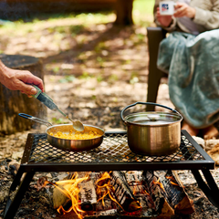 Campfire cooking kit being used on an open campfire making mac and cheese