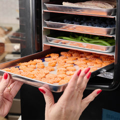 Person putting in a Home Freeze-drying system tray with carrots into the 4Patriots Home Freeze-drying system along with other fruits, vegetables and meat.