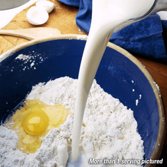 Milk being poured into a bowl with flour and an egg.