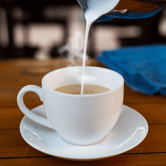 Milk being poured into a cup of coffee.