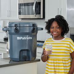 Little girl holding glass of water from the Patriot Pure Outdoor Filtration System