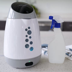 Patriot Pure Sanitizing Solution Machine on the counter next to a spray bottle.