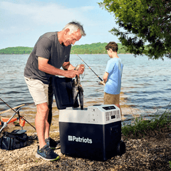 Man and boy fishing next to a lake using the 4Patriots Solar Go-Fridge to hold fish.